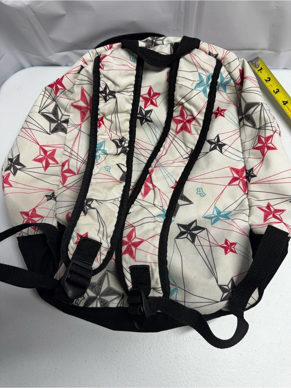 Fox Racing white polyester backpack with red, blue, and black stars and lines